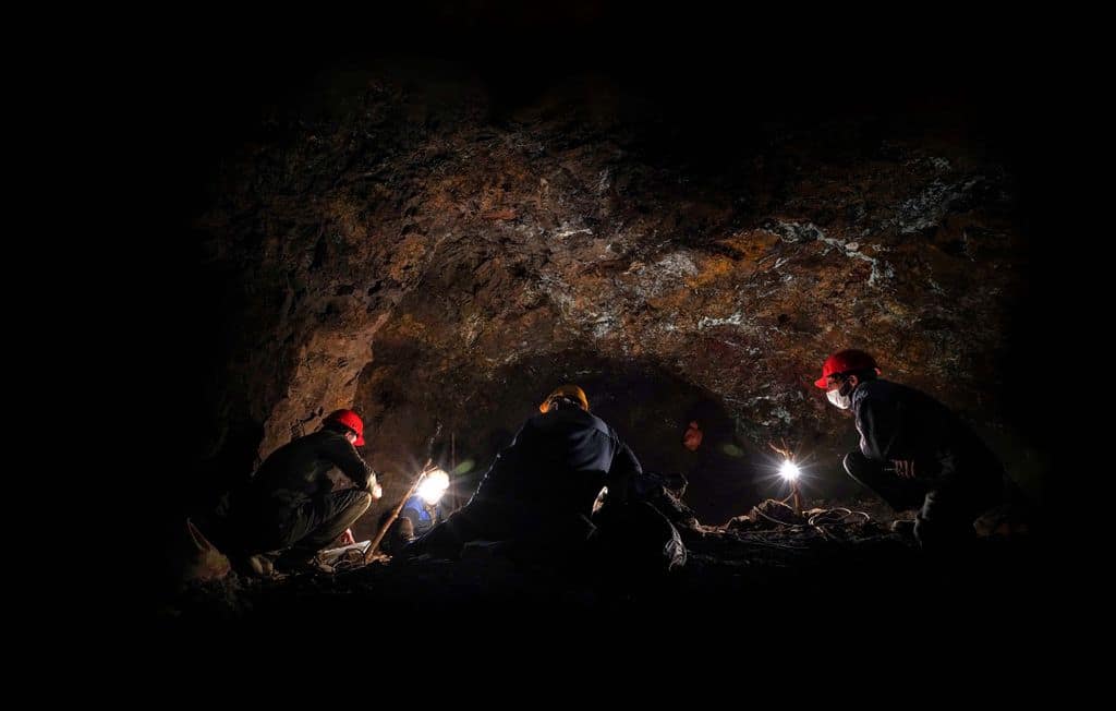 Adventurers exploring a cave in Iran at night with headlamps and hard hats.